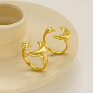 Elegant gold celestial open ring featuring moon and star design on a ceramic base