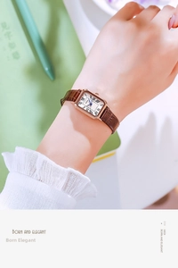 Retro rectangular rose gold watch with brown leather strap worn in an office setting