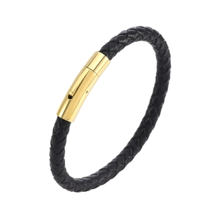 Gros plan sur la texture en cuir noir tressé et le fermoir en métal doré de ce bracelet