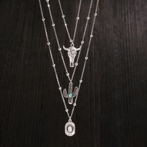 Macro detail of bohemian layered silver necklace with bull skull and cactus turquoise charms