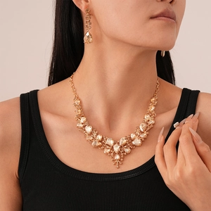 Detailed view of the champagne gold teardrop crystal necklace and earring set on a model