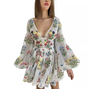 Detailansicht bunter Blumenstickerei und Netzstruktur am weißen Kleid mit Laternenärmeln