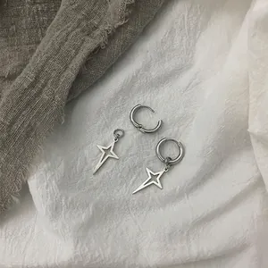 Orecchini a cerchio con stella d'argento per uomo e donna su sfondo di lino grigio scuro