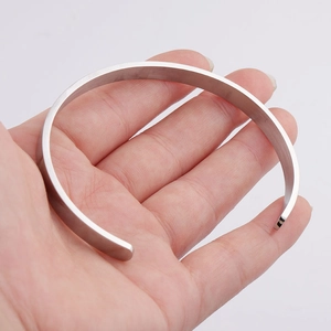 Close-up of silver brushed stainless steel C-shaped open bangle held by hand