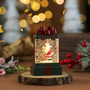 Close-up of a Santa Claus water snow globe in a green gift box shape with red bow