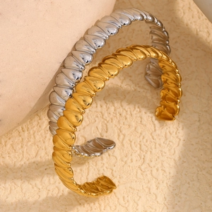 Macro view of gold and silver plated stainless steel bangles with ribbed wave pattern