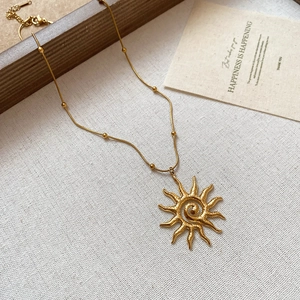 Dettaglio della collana dorata con ciondolo a spirale solare su tessuto e base in legno
