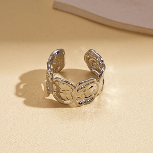 Gros plan d'une bague ouverte argentée au design géométrique et texture lave abstraite