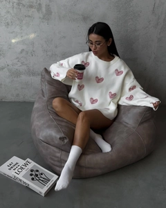 Cozy white round-neck sweater with red hearts in a relaxed home setting