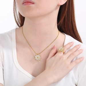 Detail of gold flower necklace and ring set with pearls and clear crystals on model