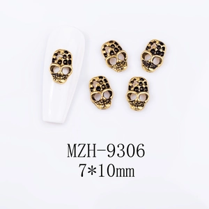 Macro detail of 7x10mm vintage gold skull nail charms for Halloween nail art designs
