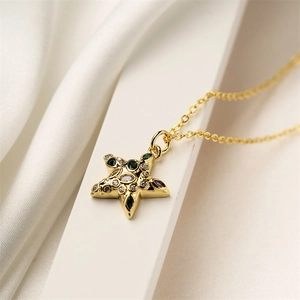Macro shot of gold star pendant necklace with colorful gems on a white jewelry box