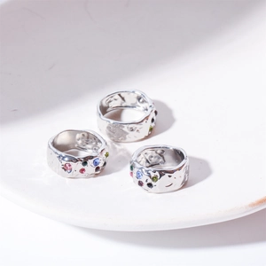 Close-up of three hammered texture silver rings with colorful zircons on ceramic tray