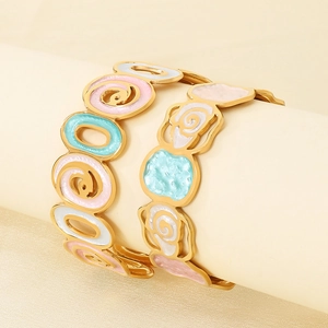 Detail of gold enamel bangles with colorful floral patterns on a jewelry stand