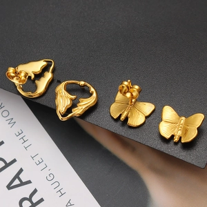 Detail of golden butterfly wing stud earrings with textured finish and metal luster