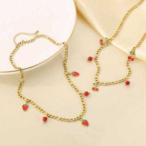 Detailed view of 18K gold plated necklaces with red enamel strawberry and cherry pendants