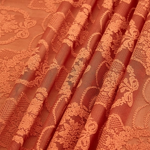 Macro view of orange lace tablecloth featuring intricate floral and bow knot embroidery