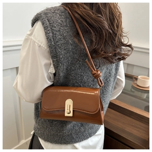 Close-up of brown glossy shoulder bag featuring a gold buckle and knotted strap detail