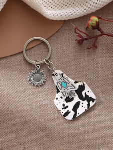 Detail of vintage cow print leather keychain with sunflower charm and eagle pendant