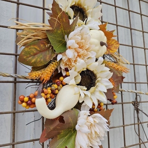 Detail von herbstlichem Tropfengesteck mit weißen Sonnenblumen, Kürbissen und Ahornblättern