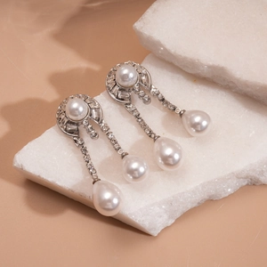 Silver geometric drop earrings with pearls and rhinestones on white stone base