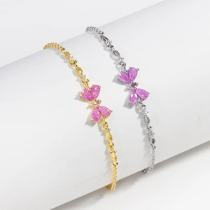 Detail of gold and silver heart bracelets with pink zircon butterfly charms on pedestals