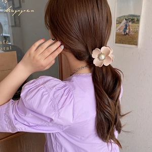 Elegant pink flower hair claw clip with white pearl detail on woman's hairstyle