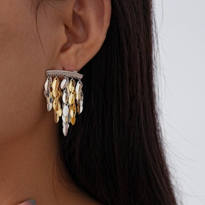 Detailed view of silver and gold metal leaf tassel earrings on a model's ear