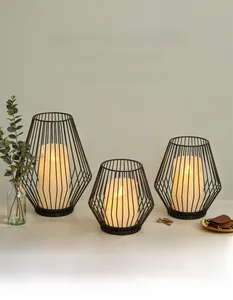 Three-piece black geometric iron lantern candle holders set on a warm wooden tabletop
