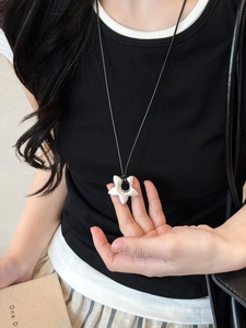 Close-up of minimalist silver star pendant with matte finish on black cord necklace