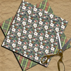 Close-up of vintage Christmas scrapbooking paper with floral patterns and a gold scissor