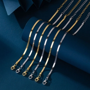 Detail view of gold and silver flat snake chains on a blue minimalist display