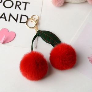 Detail of red faux rabbit fur cherry keychain with green leather leaves and gold clasp