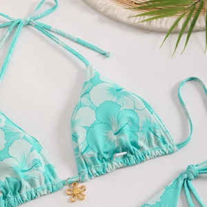 Detail of teal floral bikini top with neck ties and a gold petal-shaped metal pendant