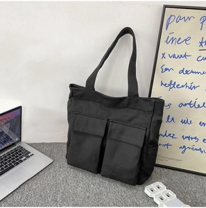 Detail of black canvas tote bag showing two large front pockets and durable material