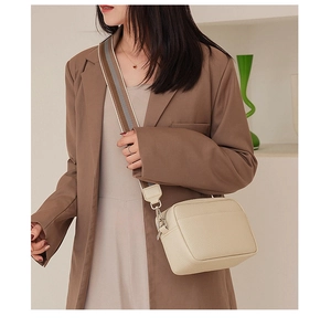 Detail of off-white crossbody bag with lychee texture and wide striped canvas strap
