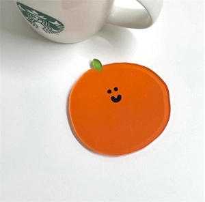 Cute orange-shaped acrylic coaster with a smiley face and leaf detail on a white surface
