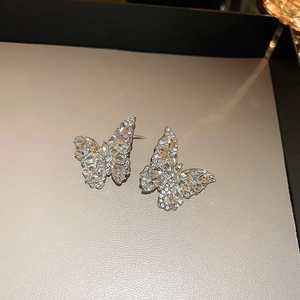 Detailed close-up of butterfly stud earrings with sparkling crystals on a neutral base