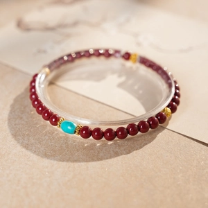 Close-up of cinnabar beaded bracelet with turquoise focal stone and golden metal spacers
