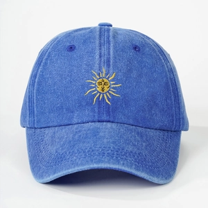 Close-up of golden sun embroidery on washed blue denim cotton baseball cap