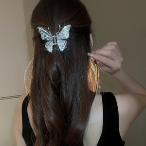 Detailed view of butterfly hair claw clip with sparkling rhinestones on dark hair