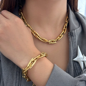 Detail of chunky gold chain necklace and bracelet set on a dark grey suit jacket