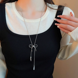 Detail of silver bow pendant necklace with cascading tassels on elegant Y-chain style