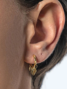 Close-up of gold geometric hoop earrings with rhombus fringe on model's ear