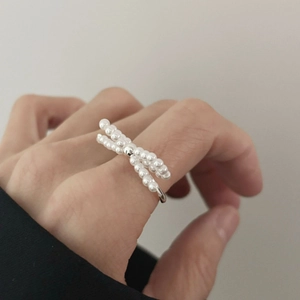 Detailed shot of bow-shaped ring with small white pearls on 925 sterling silver band