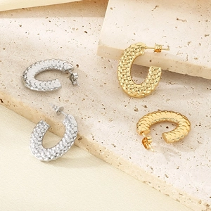 Detailed view of C-shaped gold and silver earrings with vintage hammer pattern texture