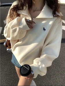 Λεπτομέρεια κεντήματος μονόκερου σε κρεμ oversized φούτερ με μισό φερμουάρ για γυναίκες