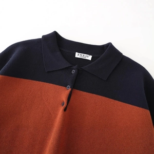 Navy and orange color block polo knit sweater with buttoned collar on white background