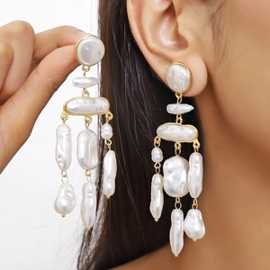 Macro detail of Baroque pearl drop earrings with elegant gold-plated frames on model