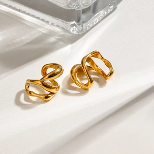 Makro-Detail von unregelmäßigen hohlen goldfarbenen Edelstahl-Ohrklemmen mit Politur